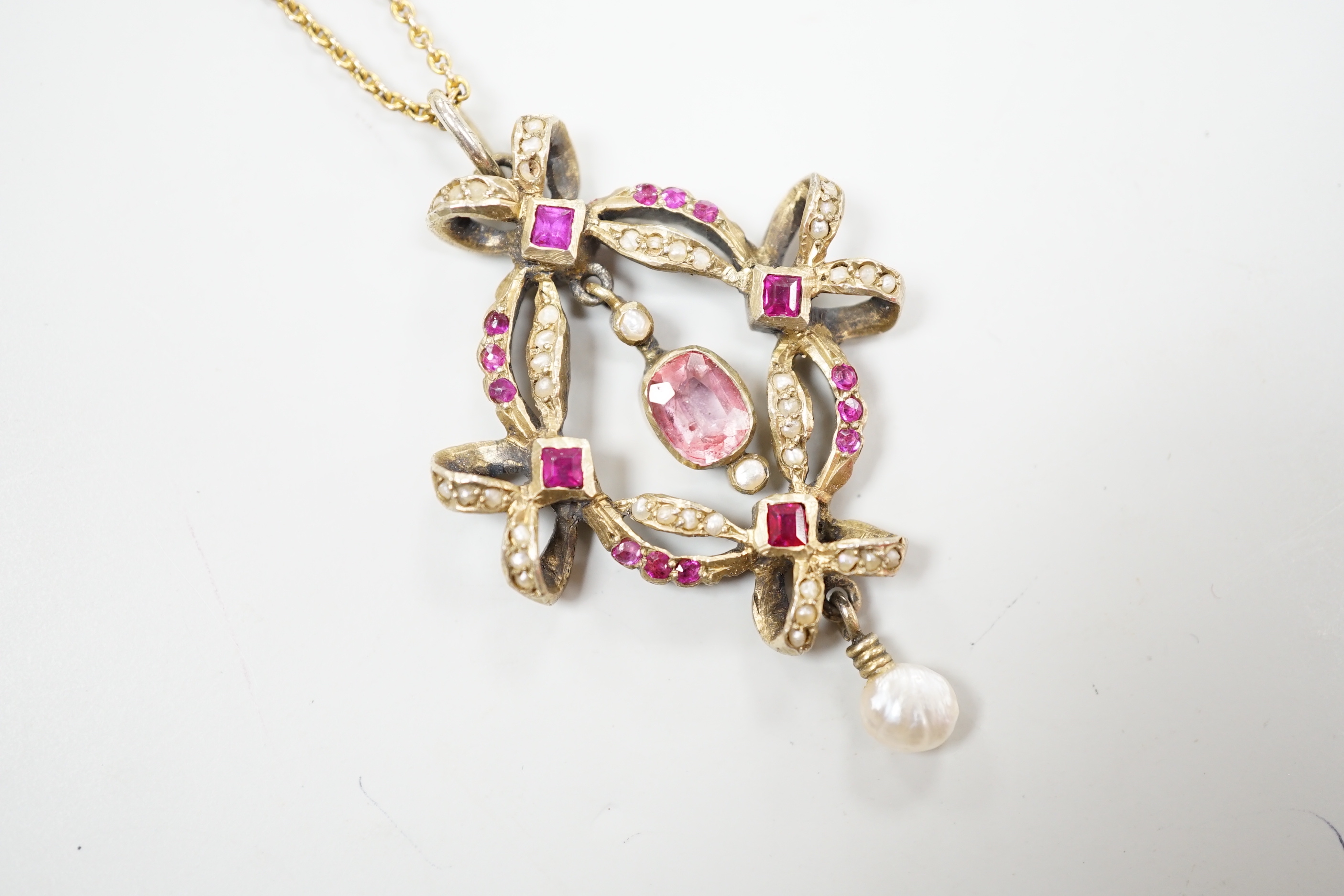 An early 20th century Continental gilt white metal pendant set with rubies, seed pearls and other gems, on a fine gold chain, leather cased, pendant 4.5cm
